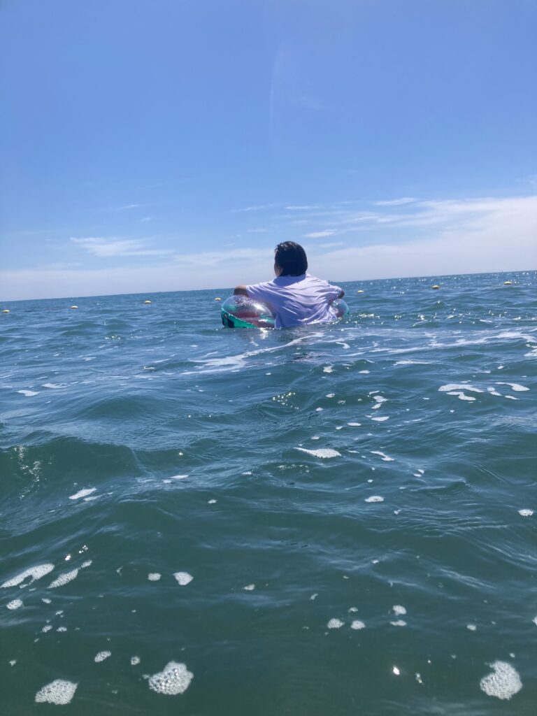 前原海水浴場で浮き輪に乗って波乗りしている男の子。